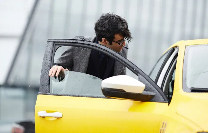Bărbat care deschide ușa unui taxi galben ca să urce